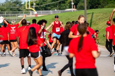 A runner makes his way through the H-F Marching Band line as they storm across, high-fiving runners on the way. (ABS)