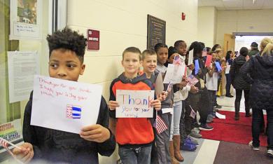 Students line the hall of James Hart school with handwritten greetings for veterans.