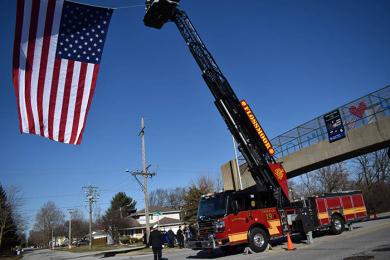 Flossmoor fire department engine 19 takes part in hanging an American flag in honor of fallen Chicago Heights officer Gary Hibbs. The flag was draped on Halsted Avenue during Hibbs' funeral. (MC)