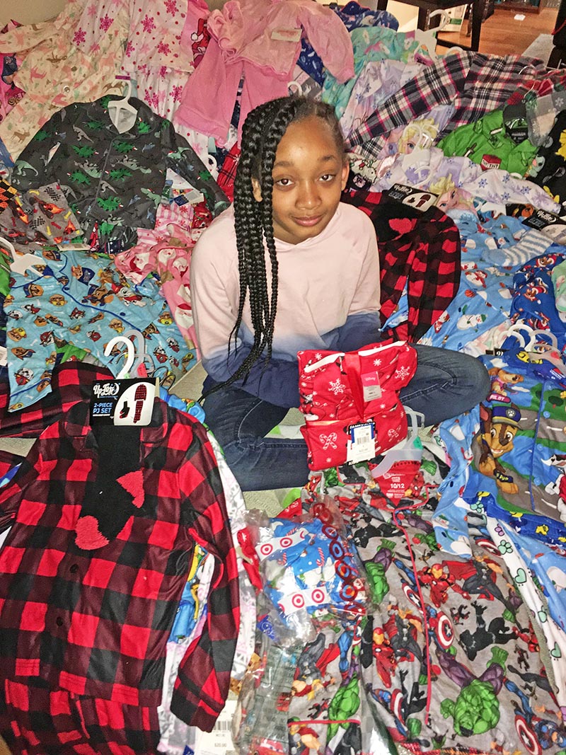 Ten-year-old Homewood resident Dannen Rose sits among some of the 300 pairs of pajamas she helped collect for patients at Lurie Children's Hospital. (Carole Sharwarko/HF Chronicle)