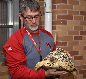 H-F High teacher Christopher Stiglic holds a tortoise given to the Zoo/Bots Club. (Photo by Mary Compton/H-F Chronicle)
