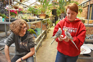 Bobby Sterning of Chicago Heights has a macaw perched on his shoulder while Emily Komorowski of Flossmoor talks about two lovebirds in the zoology lab. (Photo by Mary Compton/H-F Chronicle)