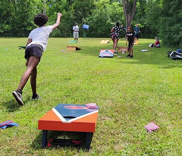 Tai Jordan, left, and Cameren Jordan, in the black T-shirt, play a game of bag toss at the 4th of July community picnic. (EC)
