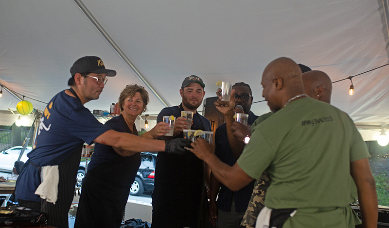 The two teams of chefs plus DJ Phil Lee raise their glasses in cameraderie at the second Battle of the Chefs fundraiser on July 9. (Provided photo by Marcellus Marsh/Bionic Content)