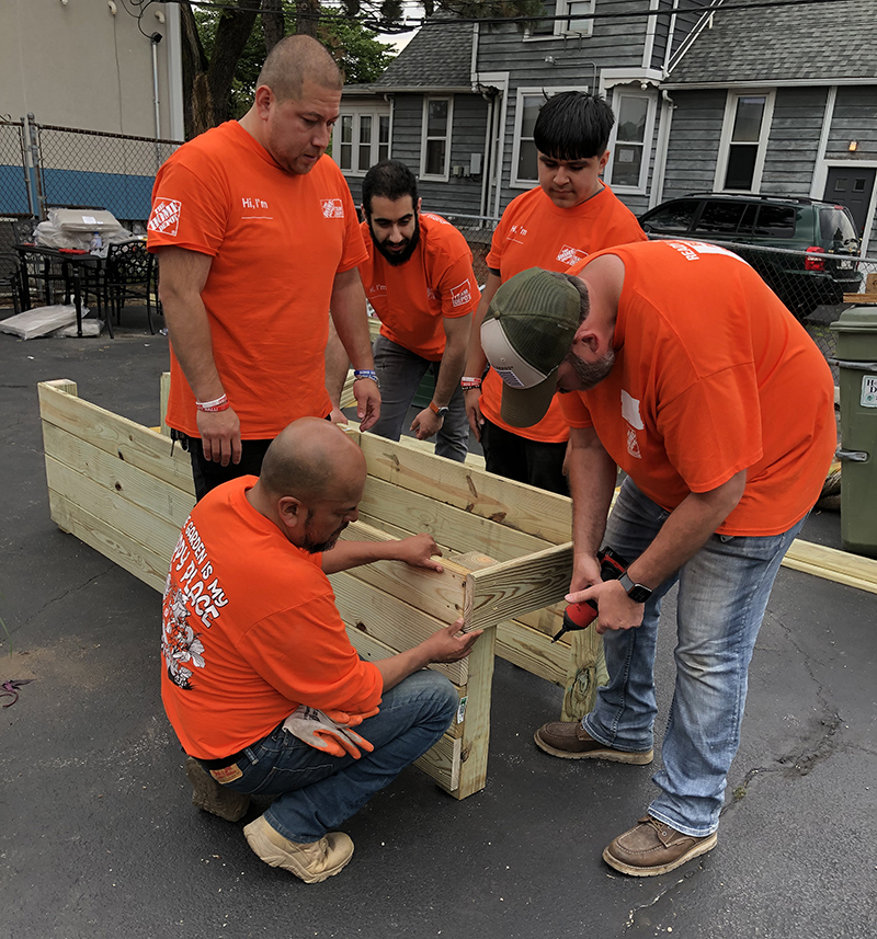 A team of Home Depot employees work at assembling a standing flower bed frame to be used at the Homewood Cancer Support Center. (Marilyn Thomas/H-F Chronicle)