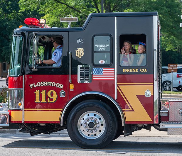 july4parade_220704_2 Two kids wave from a firetruck while leading the Flossmoor 4th of July parade at Parker Junior High. (ABS)