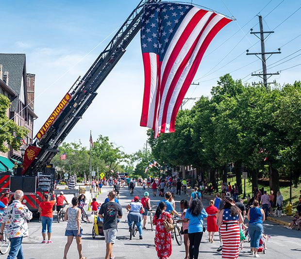july4parade_220704_6 Paraders walk underneath a massive U.S. flag held by a firetruck during the Flossmoor 4th of July parade. (ABS)