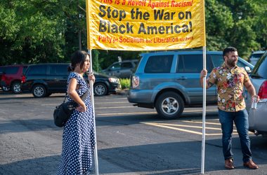 Candice Choo-Kang and Shabbir Rizvi of the Party for Socialism and Liberation (PSL) hold a banner that reads "Stop the War on Black America!" outside of Flossmoor village hall on Monday, July 18. (Andrew Burke-Stevenson/H-F Chronicle)
