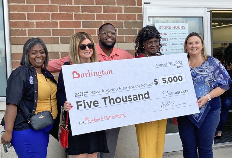 Juli Majorney, the principal of Maya Angelou Elementary School in Harvey, right, accepts a $5,000 donation from Burlington on the store's opening day, Aug. 26. (Provided Photo)
