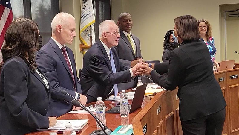 Karen Washington, right, shakes hands with Homewood Mayor Rich Hofeld as she bids farewell to the board after serving as a trustee for eight years. (Eric Crump/H-F Chronicle)