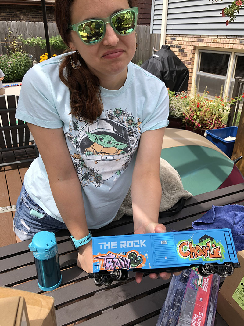 Holly Hentschel Dominik shows off her handiwork. She paints graffiti only box cars for the Hentschel model train event. (Marilyn Thomas/H-F Chronicle)