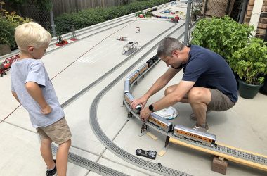 Mason Foss, 4, waits for Bill Ipema to get the train cars coupled. (Marilyn Thomas/H-F Chronicle)