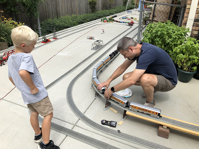 Mason Foss, 4, waits for Bill Ipema to get the train cars coupled. (Marilyn Thomas/H-F Chronicle)