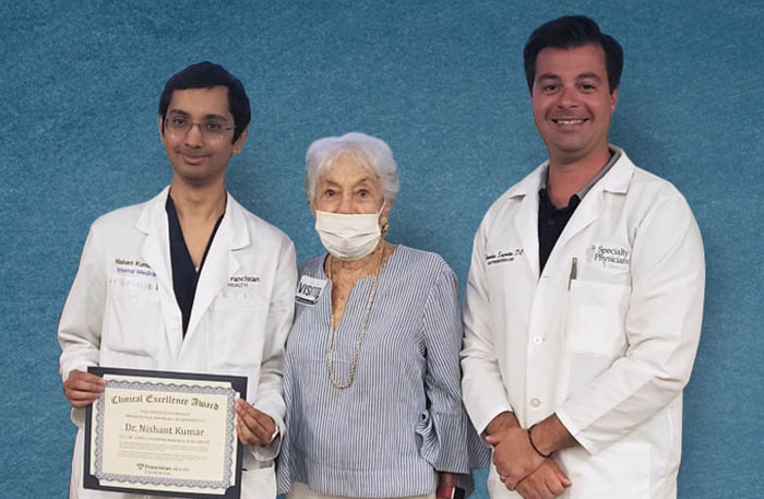 Franciscan Health resident Dr. Nishant Kumar, left, receives the Lowell Goldberg Memorial Scholarship from Dr. Goldberg’s widow Beverly Goldberg and Dr. Tilemahos Spyratos. (Provided photo)