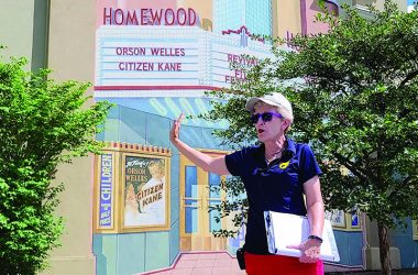 Kris Condon provides information about the Homewood Theatre mural on the south wall of Melody Mart, 18062 Dixie Highway, during a tour she conducted on July 31.