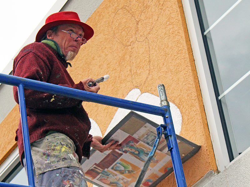 Thomas Melvin works on the most recent Haas mural in Homewood, "Independence Day," completed in the fall of 2014. (Eric Crump/H-F Chronicle)