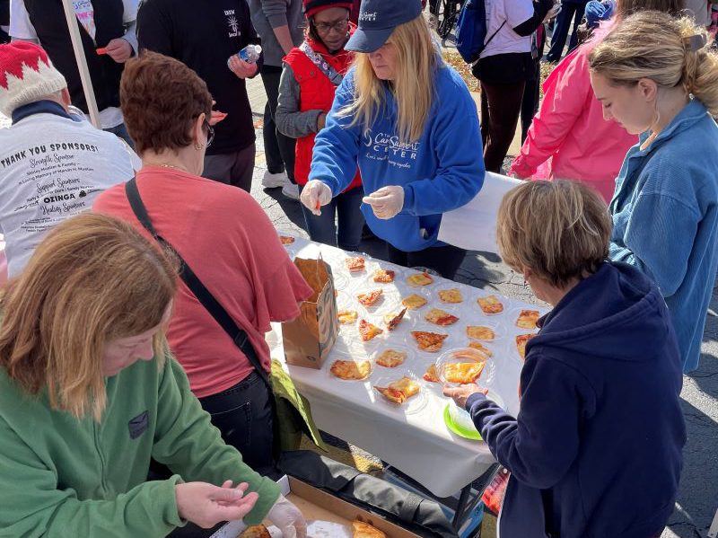 Volunteers serve up pizza donated by Aurelio's to hungry walkers. (Carole Sharwarko/H-F Chronicle)
