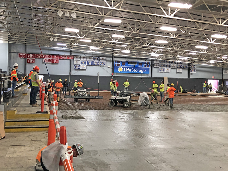 The robot machine, with its spout covered in white plastic, kept an even delivery of concrete as the Olympic-sized rink at the H-F Ice Arena is filled in. (Marilyn Thomas/H-F Chronicle)