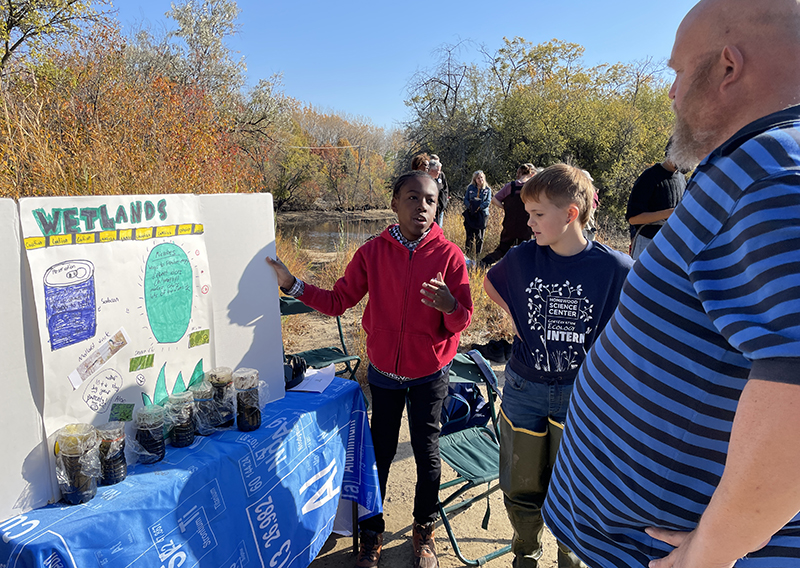 Braylen Brewer (left), of Olympia Fields, and Darby Van Vliet, of Chicago Heights, explain their wetlands conservation work to Kirby Van Vliet during the Walk Walton. (Bill Jones/H-F Chronicle)
