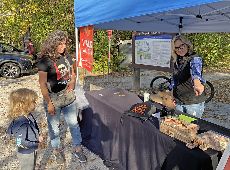 Edie Dobrez, right, executive director of the Homewood Science Center, explains Walk Walton’s activities to Kiora, 5, and Jennifer Krystosek, of Homewood. (Bill Jones/H-F Chronicle)