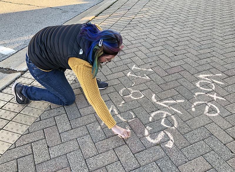 District 153 parent Sarah Young works on her message reminding commuters on their way to a train that Tuesday is voting day for District 153's referendum. (Marilyn Thomas/H-F Chronicle)