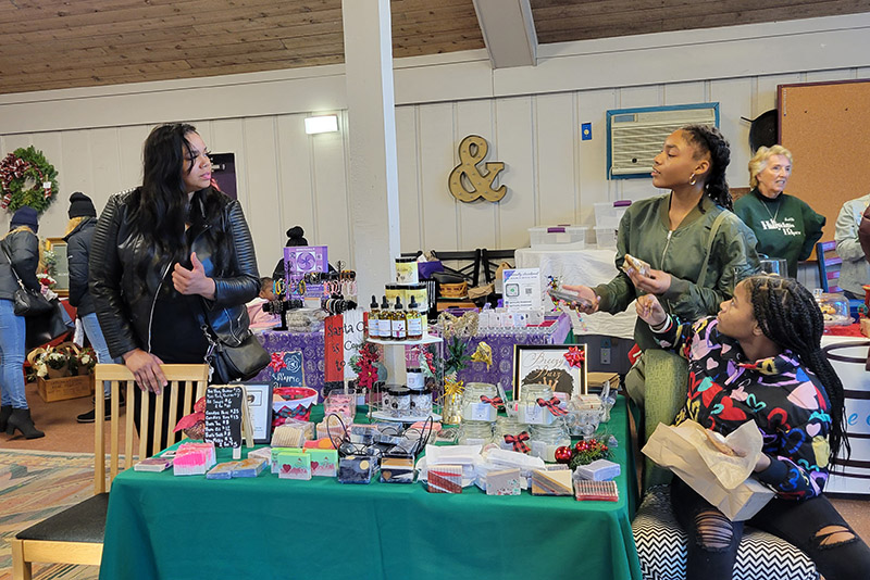 Bryeanna Howard, left, of Breezy Bars and Beauty, Chicago Heights, gets help with her popup shop from daughter, Bria, and her niece, Christian Montgomery, right. (Eric Crump/H-F Chronicle)