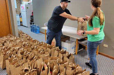 Open Access Program Director Nick Koster takes a bag of food from a volunteer on Nov. 17. More than a dozen volunteers from the youth group of the First Reformed Church of South Holland helped get meal packages organized. (Eric Crump/H-F Chronicle)
