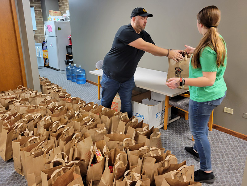 Open Access Program Director Nick Koster takes a bag of food from a volunteer on Nov. 17. More than a dozen volunteers from the youth group of the First Reformed Church of South Holland helped get meal packages organized. (Eric Crump/H-F Chronicle)