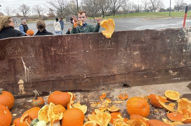 Jeremy Martin, a student volunteer from Parker Jr. High School, tosses the remnants of pumpkins into a bin donated by Homewood Disposal for compost collection. (Bill Jones/H-F Chronicle)