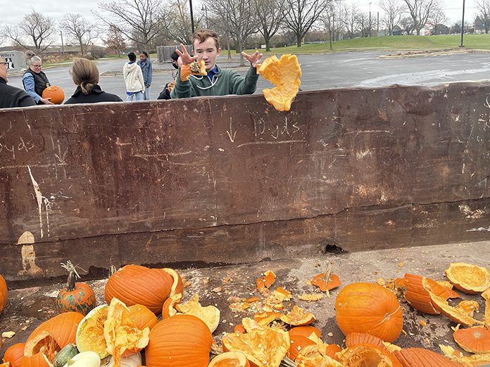Jeremy Martin, a student volunteer from Parker Jr. High School, tosses the remnants of pumpkins into a bin donated by Homewood Disposal for compost collection. (Bill Jones/H-F Chronicle)
