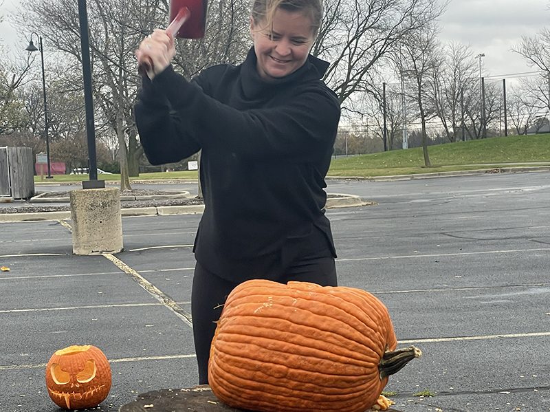 Flossmoor Mayor Michelle Nelson bashes an old gourd on a stump during the Pumpkin Smash held Saturday, Nov. 5, at Coyote Run Golf Course. (Bill Jones/H-F Chronicle)