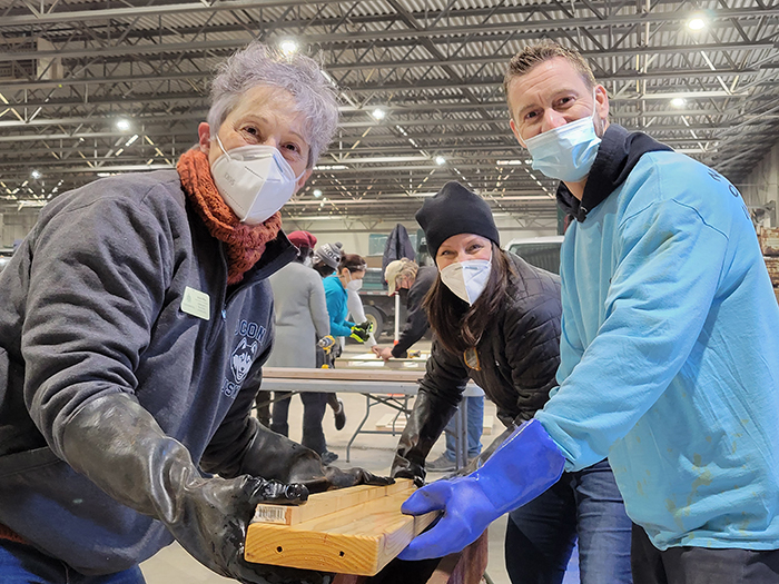 From left, Jackie Riffice, Stephanie Wright and Dave King pull a side rail from a stain solution during the Build-a-Bed event Jan. 16. (Eric Crump/H-F Chronicle)