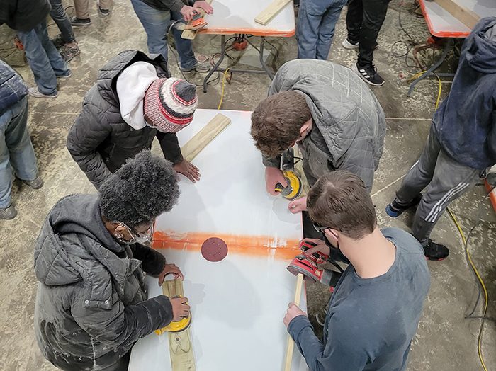 Build a Bed 2022-01-16 036 From lower left, clockwise, Amira Clemmons, Zmuzo Ugwanyi, Charlie Weeks and John Weeks help sand bed parts. (Eric Crump/H-F Chronicle)