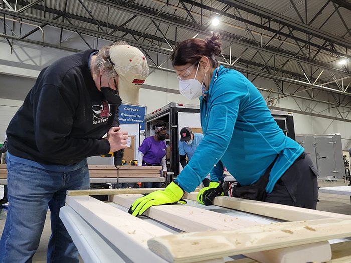 Build a Bed 2022-01-16 043 Larry Szymanski of Flossmoor wields a drill while Renee Lamb of Homewood holds the bed frame parts still. (Eric Crump/H-F Chronicle)