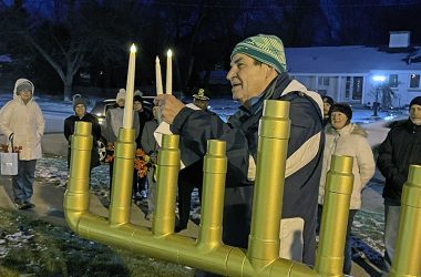 Elliott Yurman, of Homewood, lights two candles with the shamash on the second night of Hanukkah — Monday, Dec. 19 — at Flossmoor Park as community members observe. (Bill Jones/H-F Chronicle)