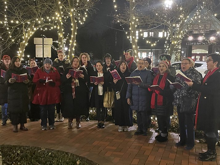 The Bel Canto Community Choir performs under the lights of the island in downtown Flossmoor the evening of Thursday, Dec. 1, for the Holiday Open House. (Bill Jones/H-F Chronicle)