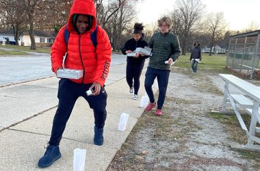 Xavier White, a National Honor Society student at Homewood-Flossmoor High School, places candles in the bags around Flossmoor Park for Light Up Your Holidays. (Bill Jones/H-F Chronicle)