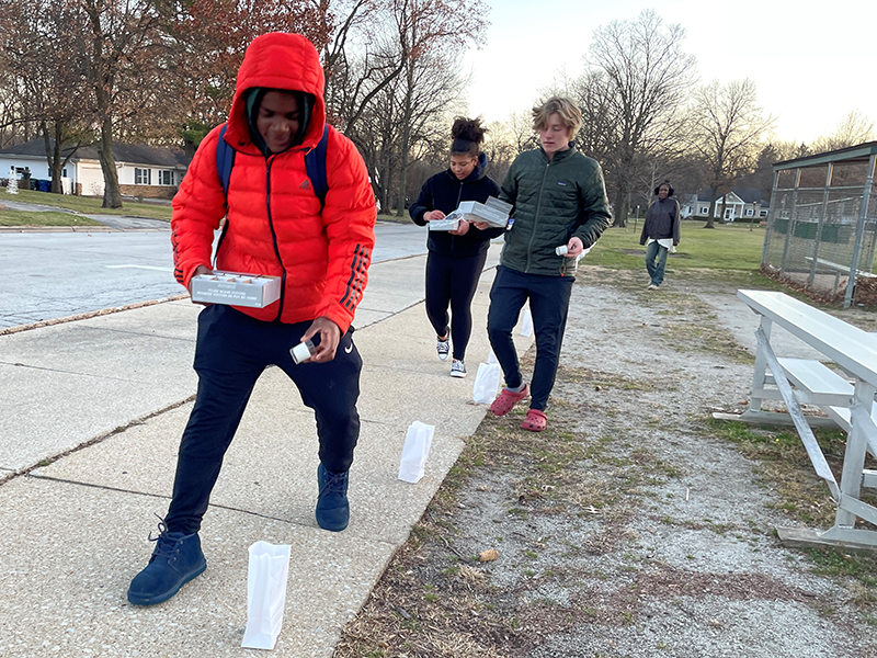 Xavier White, a National Honor Society student at Homewood-Flossmoor High School, places candles in the bags around Flossmoor Park for Light Up Your Holidays. (Bill Jones/H-F Chronicle)