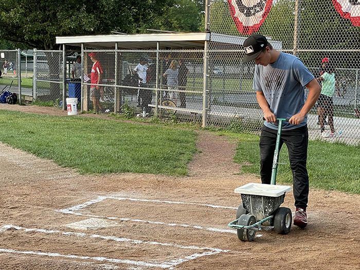 Cameron Williams, who served as home plate umpire during the championship game, paints the lines for the batter’s boxes. (Bill Jones/H-F Chronicle)