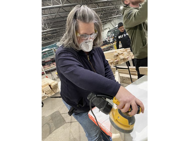 Dawn Joyce, of Oak Forest, sands a piece of wood during a bed build at the Flossmoor Public Works garage. Joyce has supported Sleep in Heavenly Peace multiple times. (Bill Jones/H-F Chronicle)