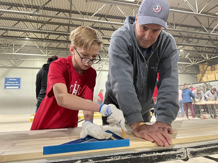 Zachary Kwiat (left), of Oak Forest, and Paul Greenawalt, of Frankfort, measure and draw segments on pieces of wood during a Sleep in Heavenly Peace bed build in Flossmoor. (Bill Jones/H-F Chronicle)