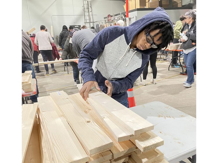 Franklin Dubose, of Park Forest, counts off pieces of wood to carry to a table. The Southland College Prep student helped with the Village of Flossmoor’s bed build. (Bill Jones/H-F Chronicle)
