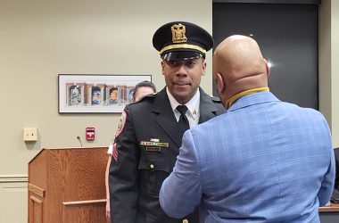 Dennis Leaks Sr., right, pins a sergeant's badge on his son, Dennis Leaks Jr. at the Homewood Board of Trustees meeting on Jan. 10. (Eric Crump/H-F Chronicle)
