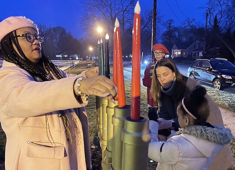 Marianne Powell and her daughter JaOni Rousseau light all seven candles on the kinara Sunday, Jan. 1, to finish the community celebration of Kwanzaa at Flossmoor Park. (Bill Jones/H-F Chronicle)