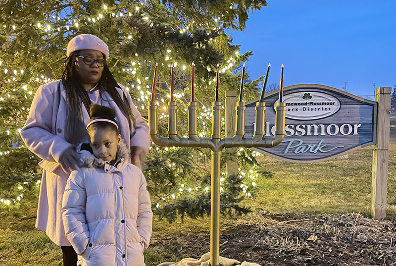 Marianne Powell reflects on how faith guided the past year of her life during a public Kwanzaa celebration in Flossmoor Park. Powell’s daughter JaOni Rousseau stands with her. (Bill Jones/H-F Chronicle)