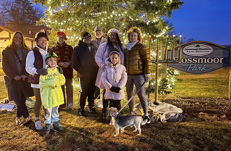 Attendees pose for a photo near the kinara with Marianne Powell and her children after the community celebrated the seventh night of Kwanzaa at Flossmoor Park. (Bill Jones/H-F Chronicle)