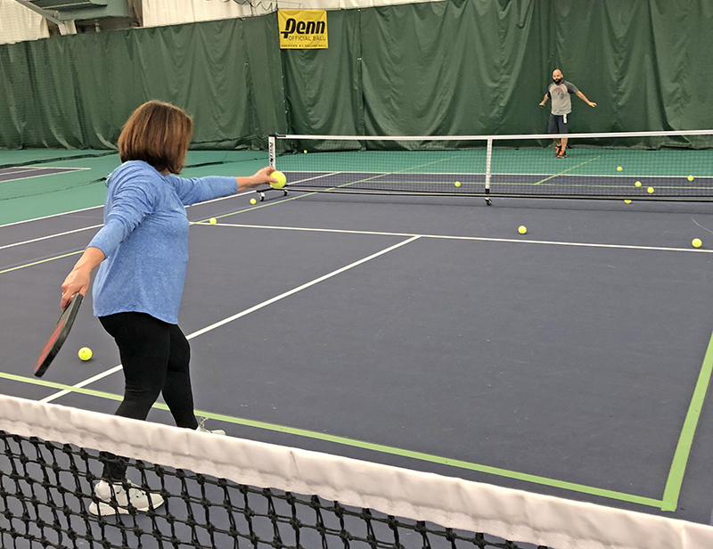 Monica Zackary practices her pickleball serves at the H-F Racquet & Fitness Club. Two pickleball courts are made from one tennis court. The net in the foreground is a tennis net. (Marilyn Thomas/H-F Chronicle)