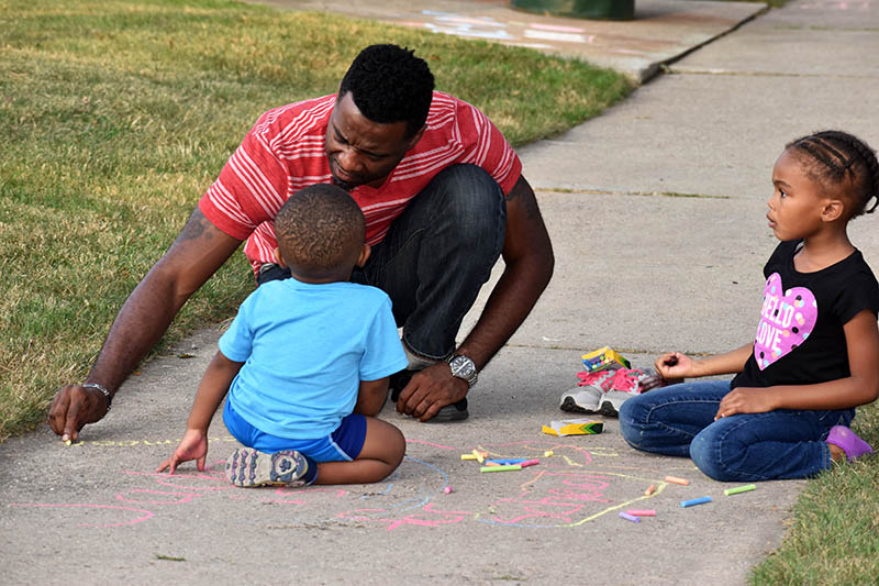 A family chalks the walk during a 2017 back to school meet and greet event.