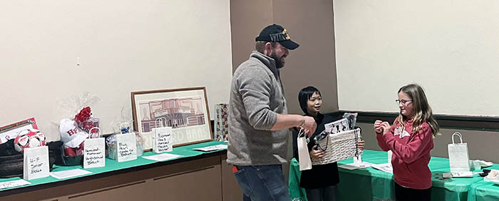 Josh Grenard of the Flossmoor Veterans Memorial Steering Committee holds a bag of raffle tickets while a volunteer reads out the winning ticket number. (Nick Ulanowski/H-F Chronicle)