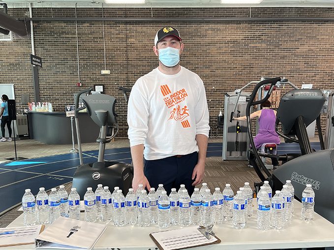 Program supervisor Brian Davis stands behind the table of water bottles for triathlon participants. (Nick Ulanowski/H-F Chronicle)
